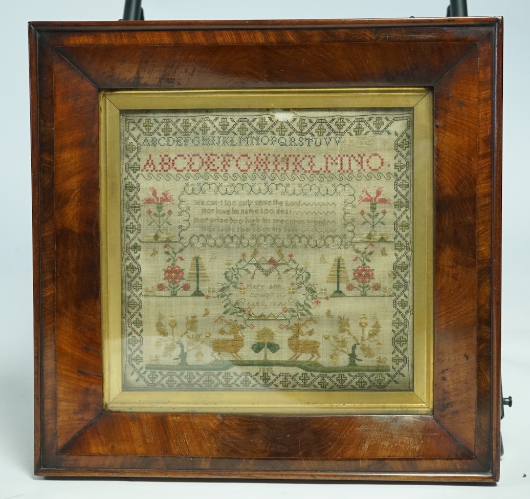 A 19th century flame figured mahogany framed cross stitch sampler dated 1842 by Mary Ann Cowell aged 10 years. Worked with the alphabet, verse and spot motifs of flowers, trees, dogs and deer, within an ornate border. 28